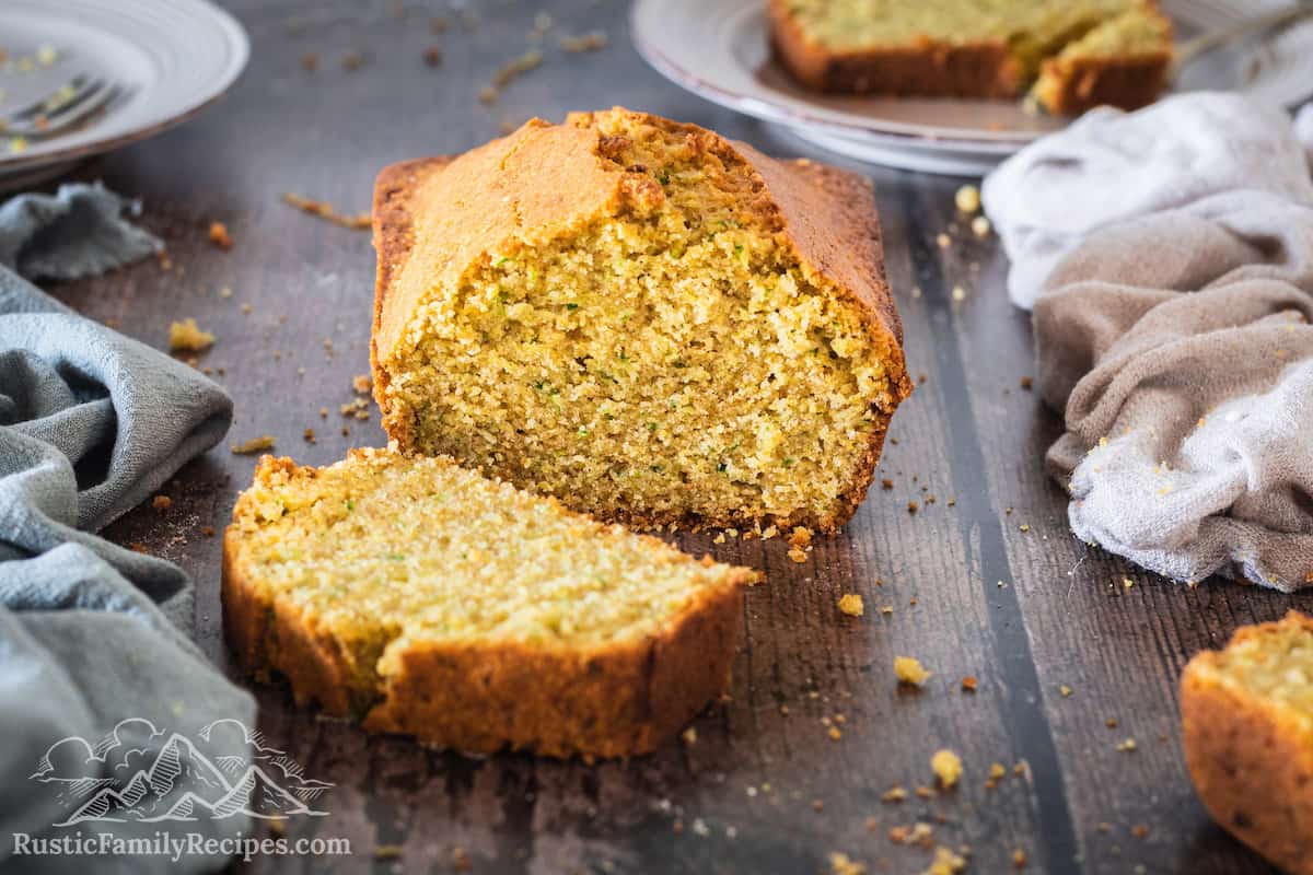 A loaf of Zucchini Cornbread with a slice cut off in front of the loaf.