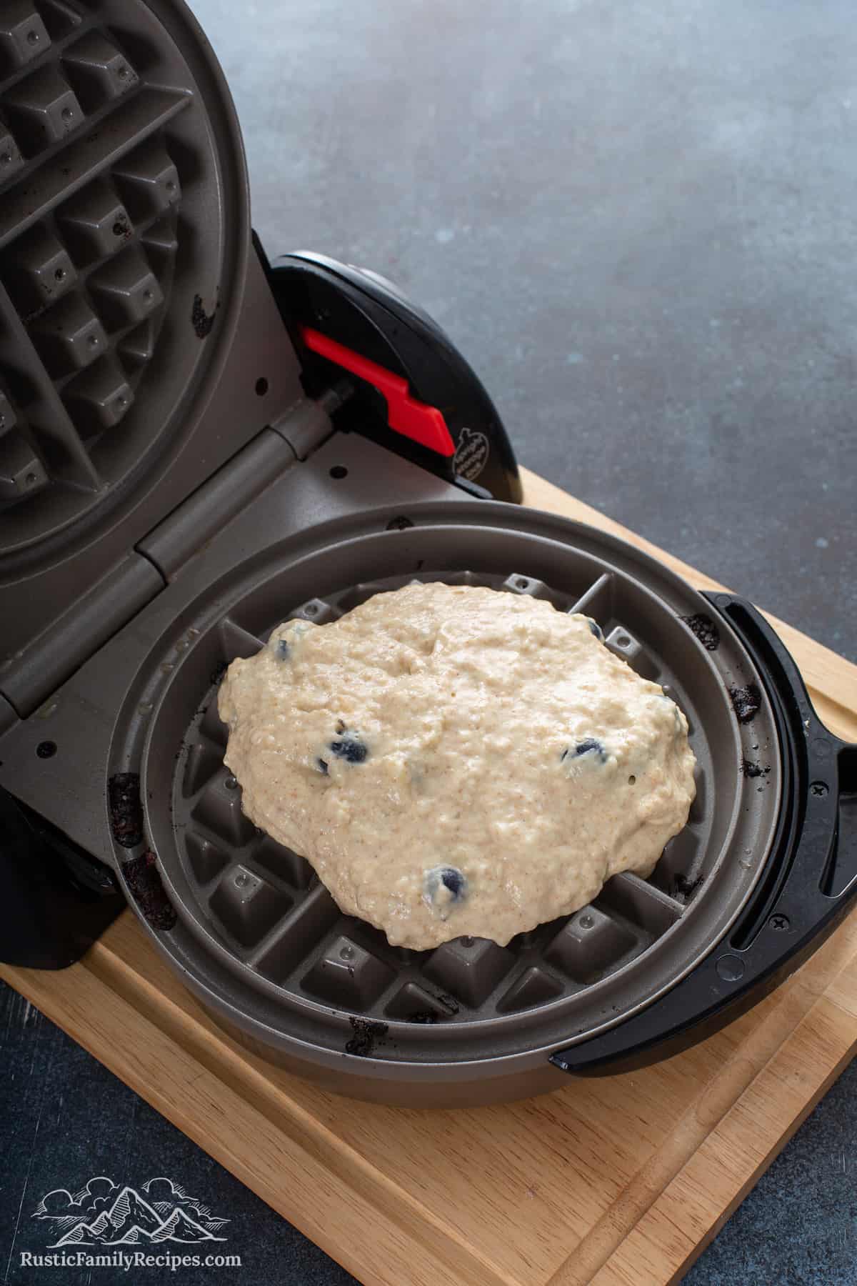 The batter spooned into the Belgian waffle maker.