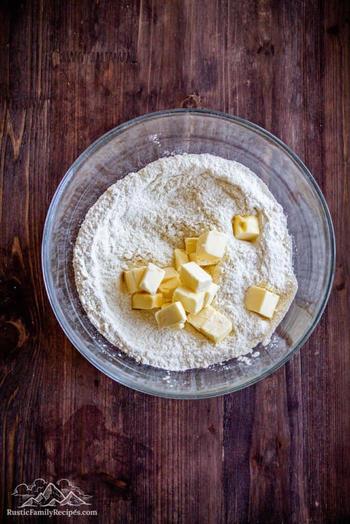 A glass bowl with flour and cubed butter