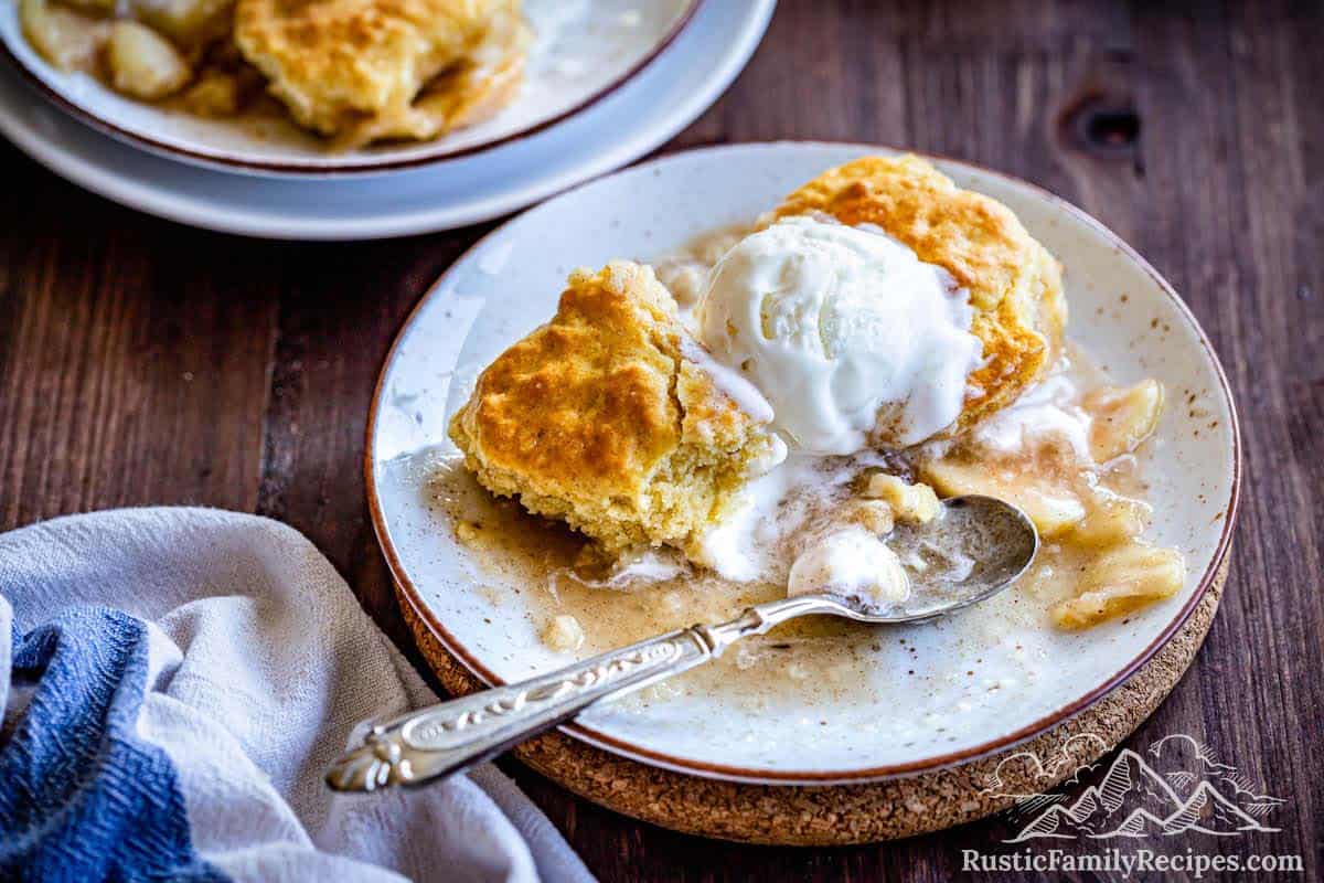 Apple cobbler with biscuit topping on a plate with ice cream