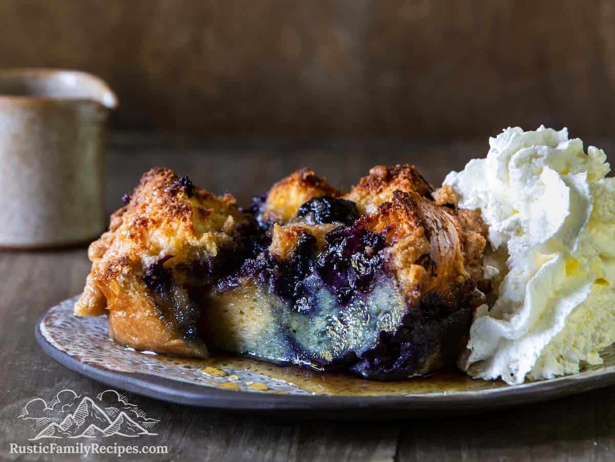 Slice of blueberry french toast bake with syrup and whipped cream