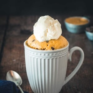 Chocolate chip peanut butter mug cake in a white mug with ice cream and a spoon