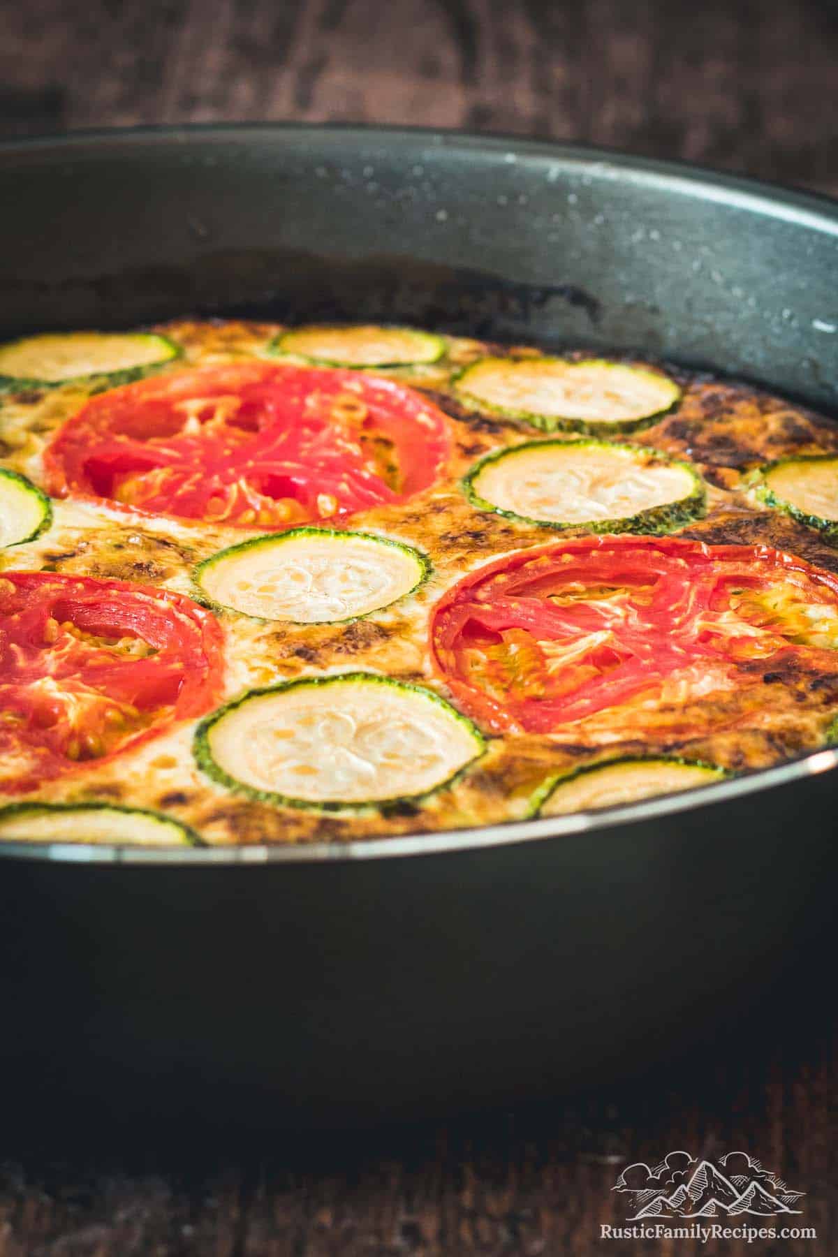 Side view of baked crustless zucchini quiche in a pan