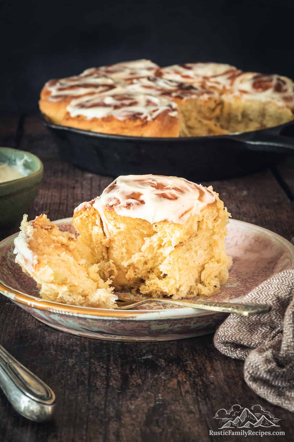 Sourdough Cinnamon Rolls on plate with cast iron skillet in background
