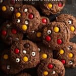 A pile of chocolate cookies with M&M candies and candy eyes.