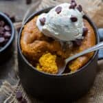 Pumpkin mug cake with vanilla ice cream and chocolate chips, spoon taking a scoop out