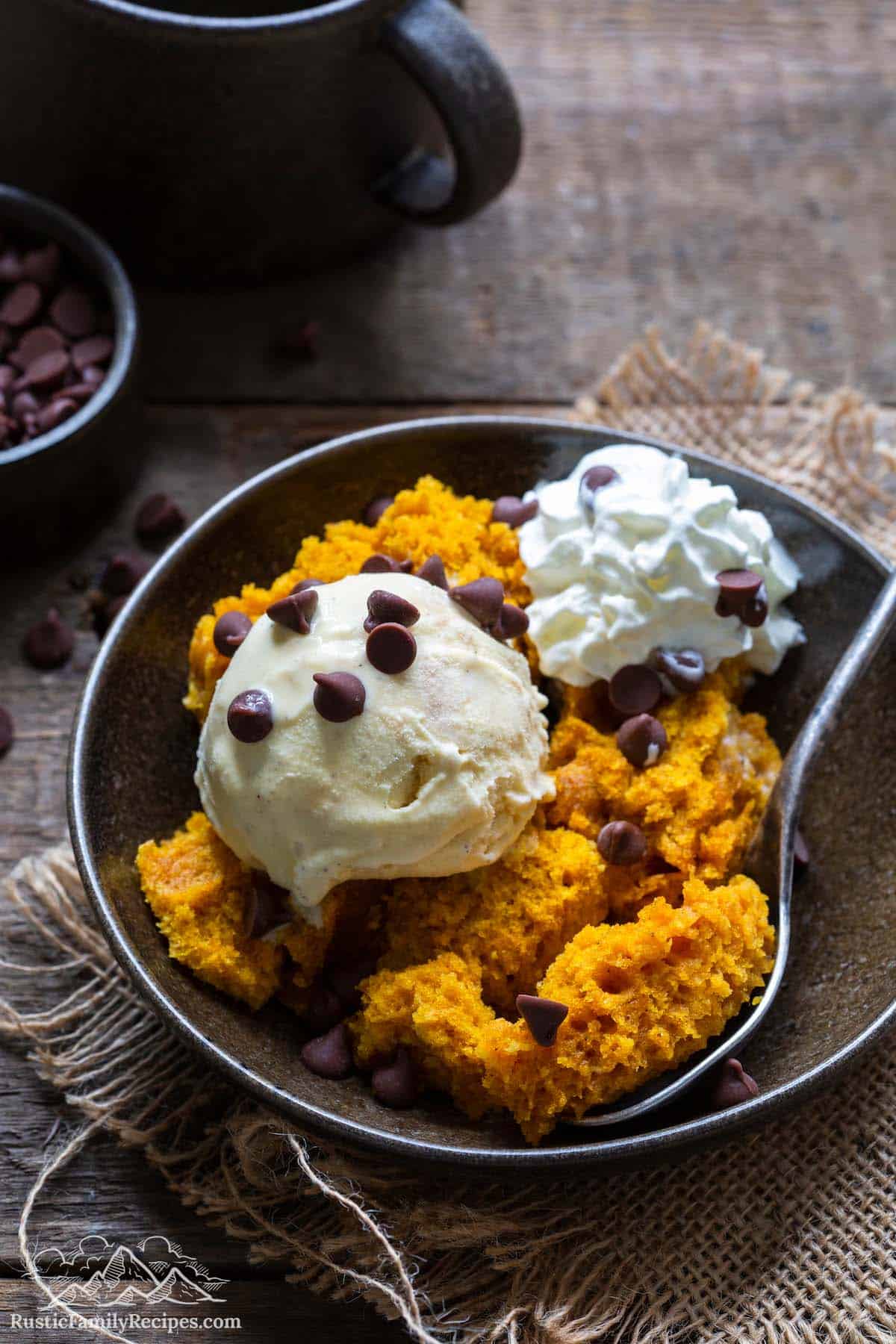 Pumpkin cake in a bowl with ice cream, whipped cream and chocolate chips