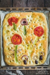 Overhead view of sourdough focaccia art bread with vegetables used to make flowers and mushrooms