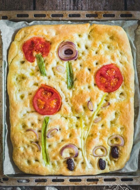 Overhead view of sourdough focaccia art bread with vegetables used to make flowers and mushrooms