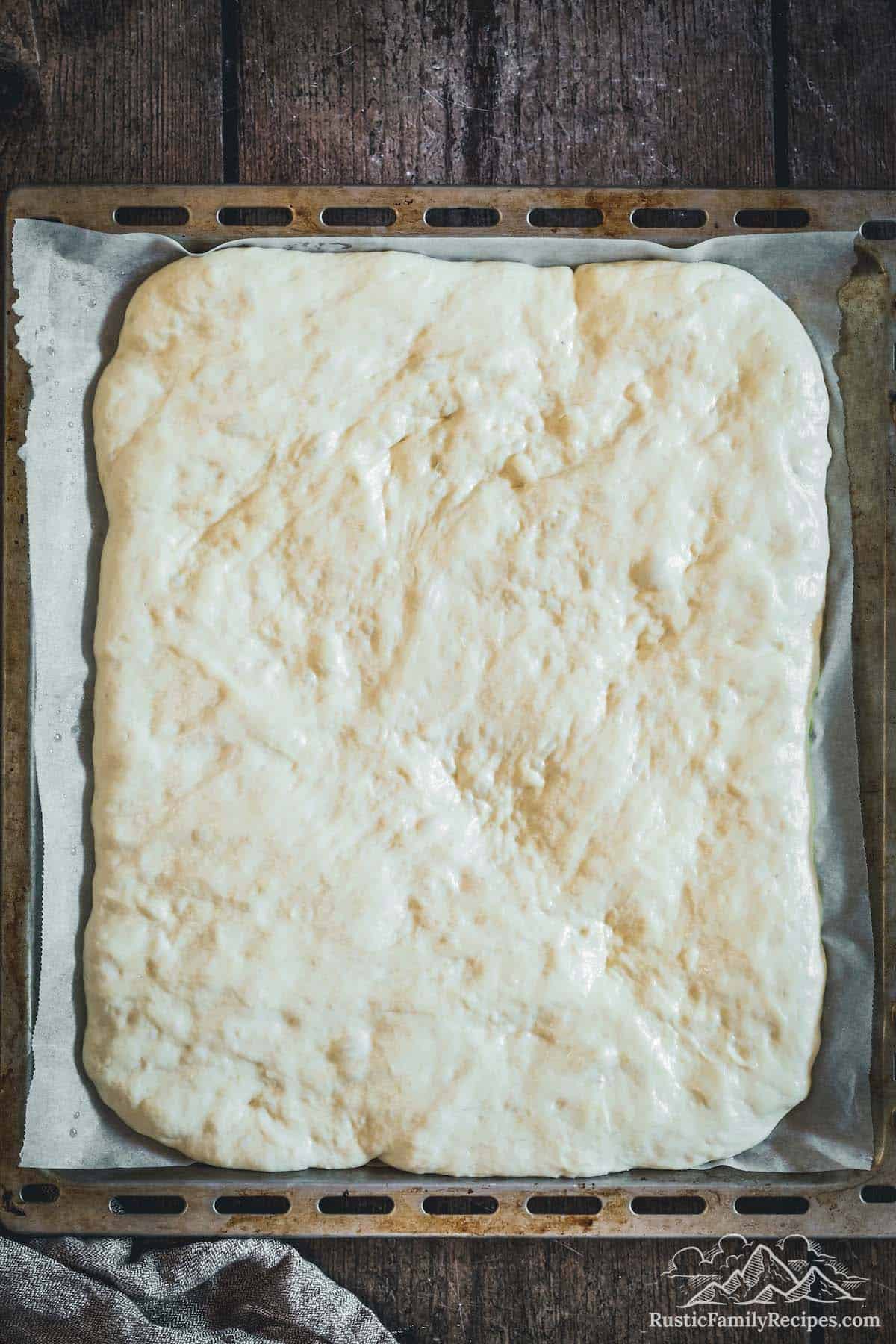 Overhead view of focaccia dough stretched out on baking sheet