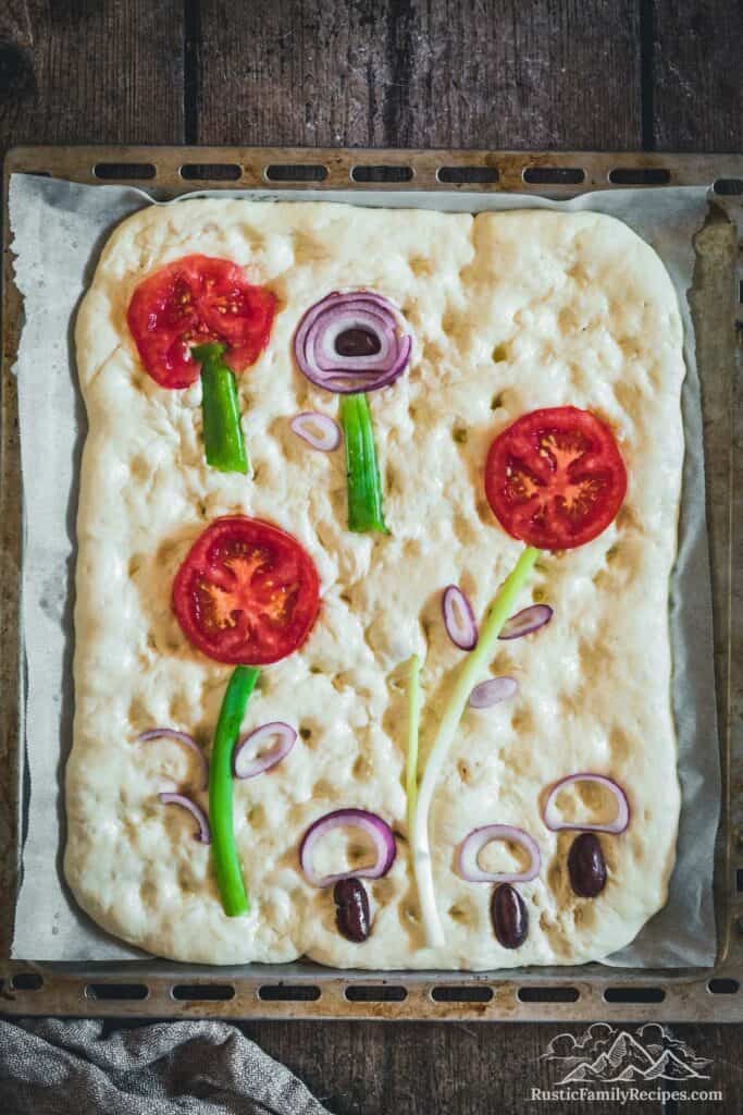 Overhead view of focaccia after arranging vegetable toppings