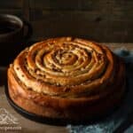 Spiral coffee cake on rustic wood table with 2 mugs of coffee in background