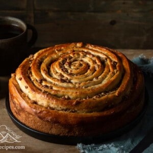 Spiral coffee cake on rustic wood table with 2 mugs of coffee in background