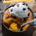 A pumpkin mug cake with ice cream and a scoop taken out.