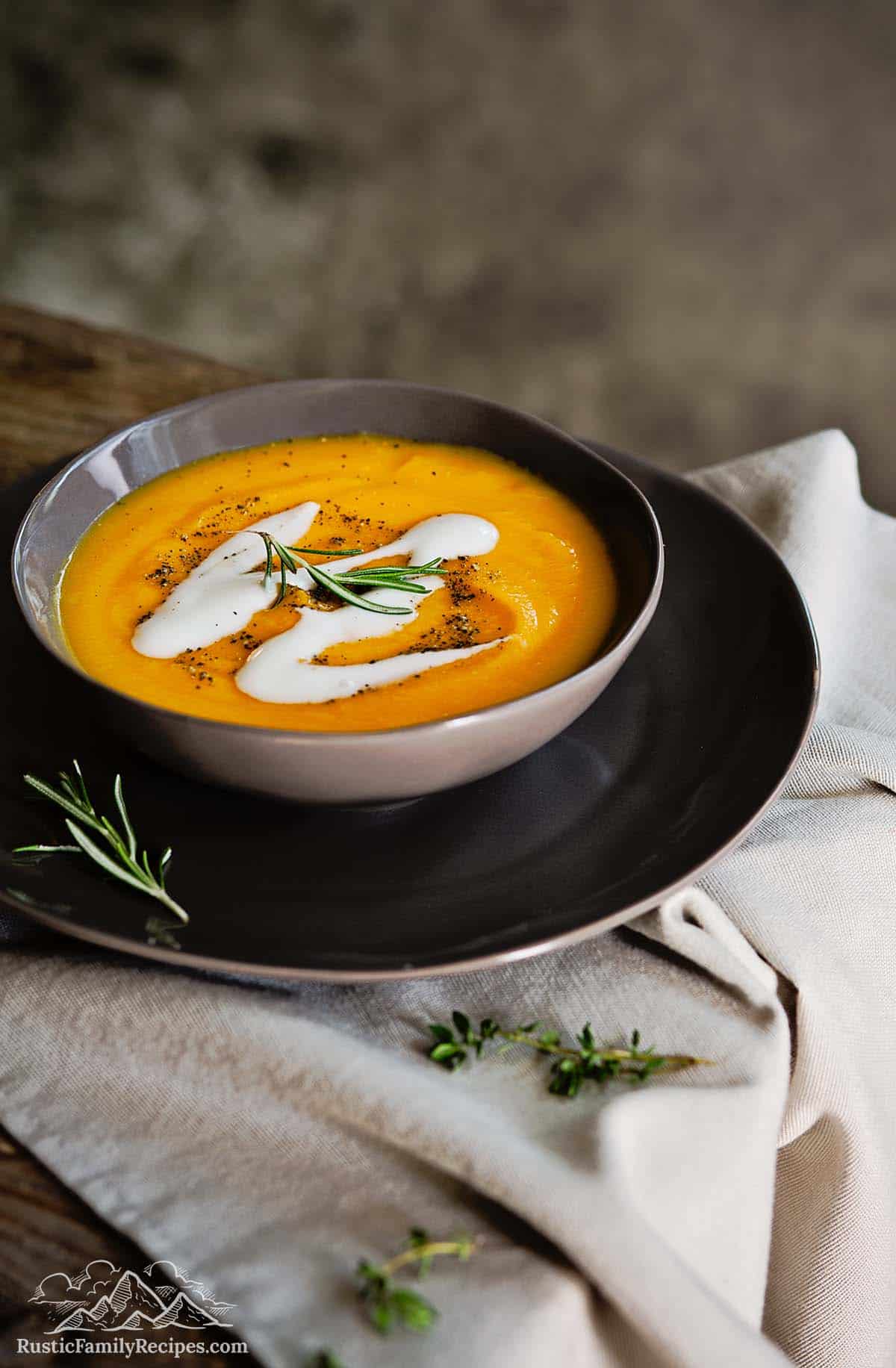 A bowl of root vegetable soup on a plate with a cloth underneath