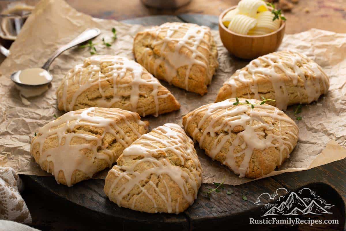 Scones arranged on brown parchment paper with bowl of butter and spoon in background