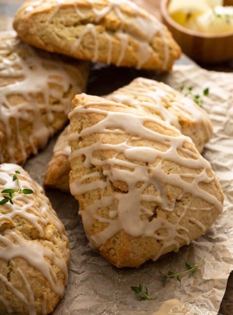 Pile of glazed maple scones on layer of parchment paper