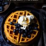 Top view of a stack of pumpkin waffles with blueberries, whipped cream and syrup