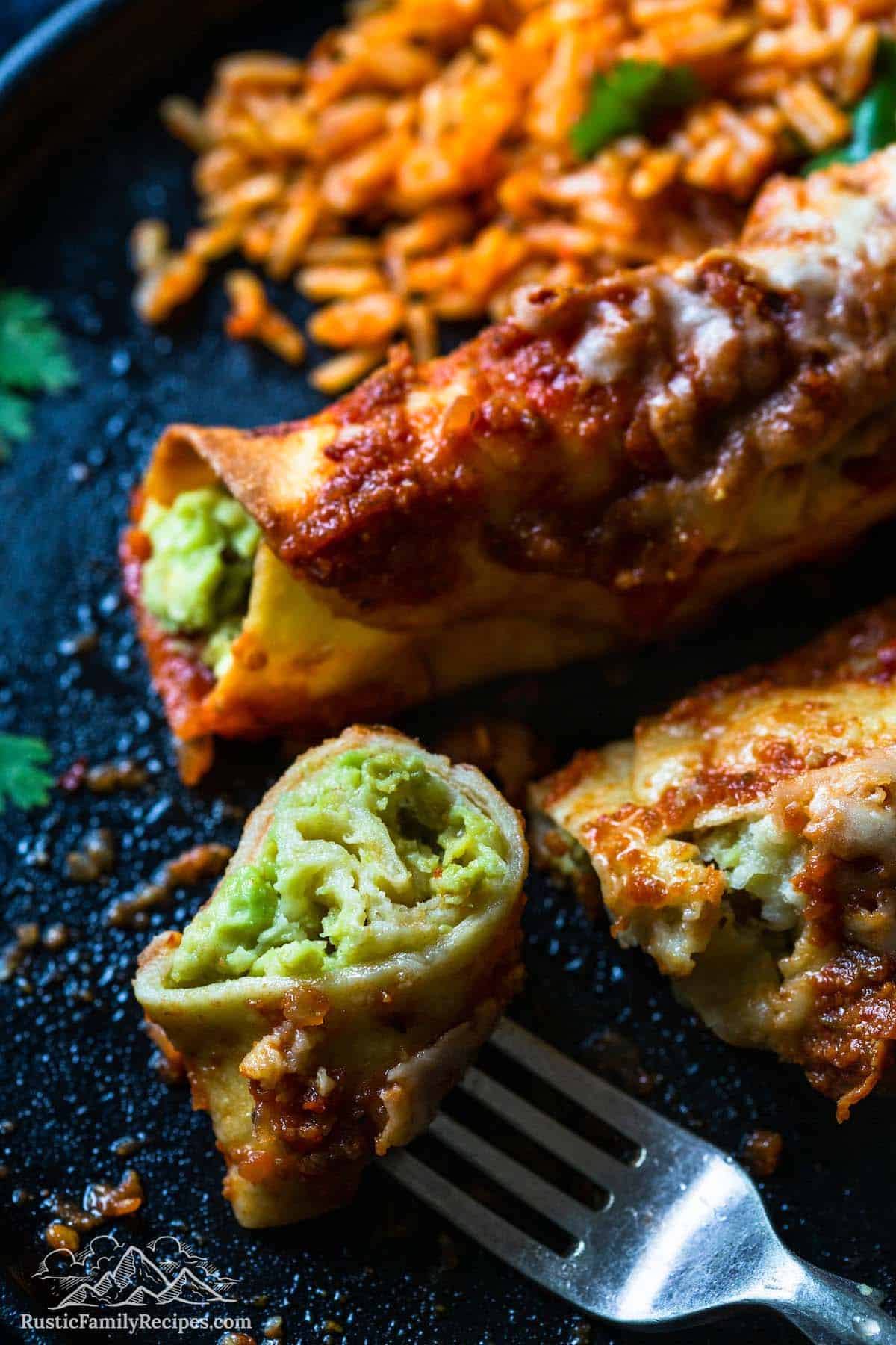 A bite of avocado enchiladas on a fork next to a plate with more food
