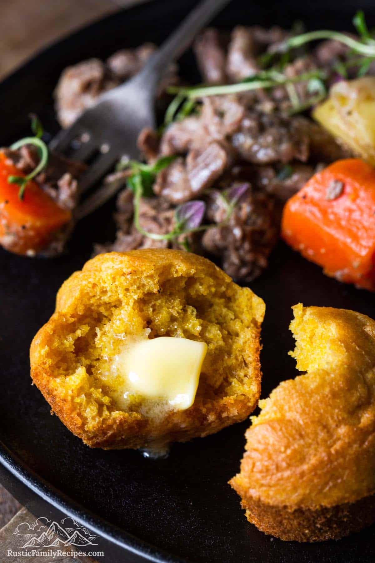 Cornbread muffins on a plate with pot roast, carrots and potatoes