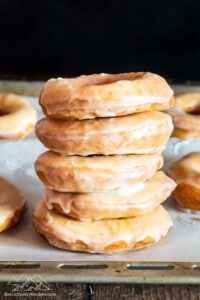 Stack of sour cream donuts on parchment lined baking sheet