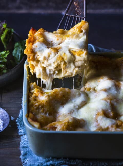 A slice of butternut squash lasagna being lifted out of a casserole dish