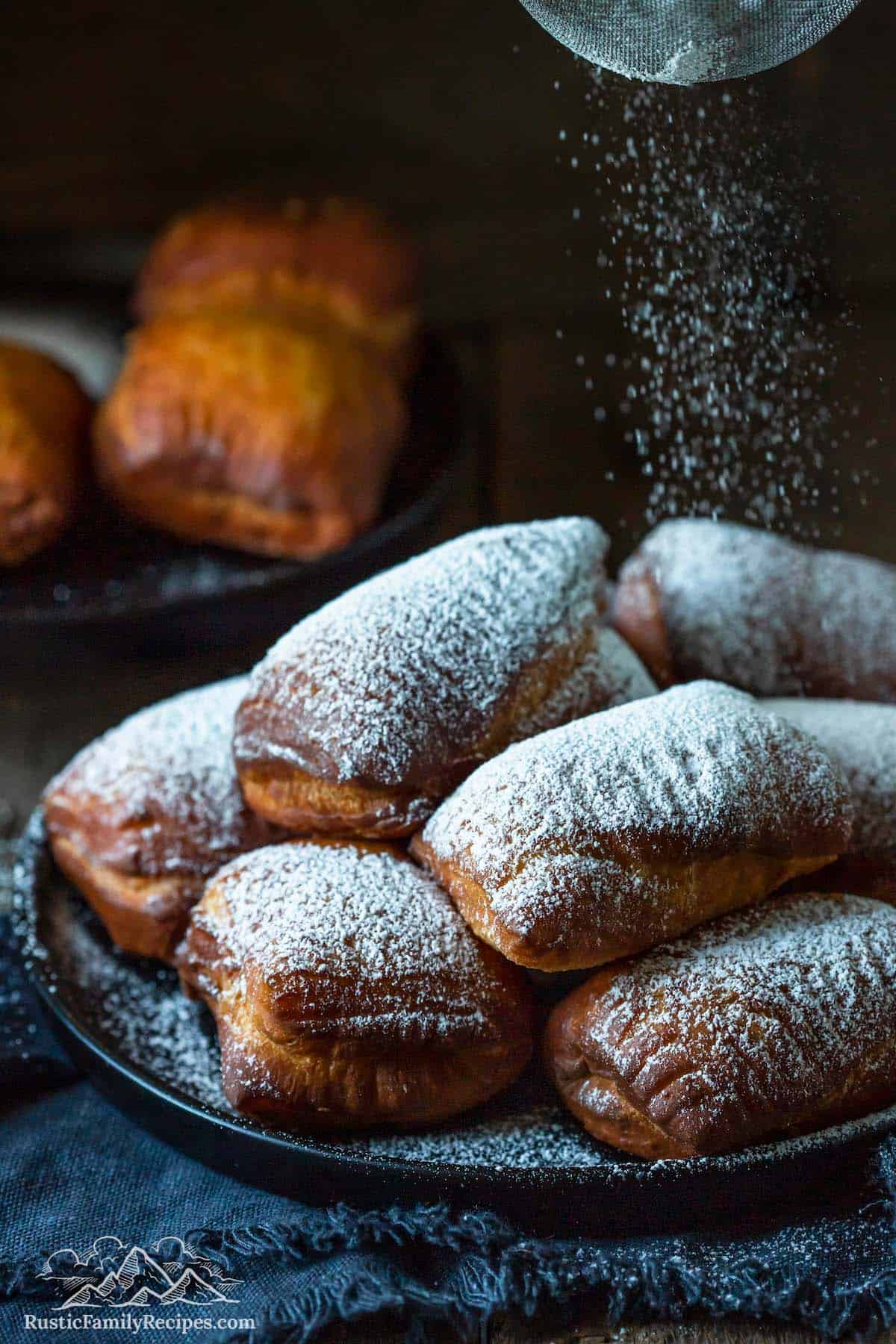 Dusting homemade beignets with sugar