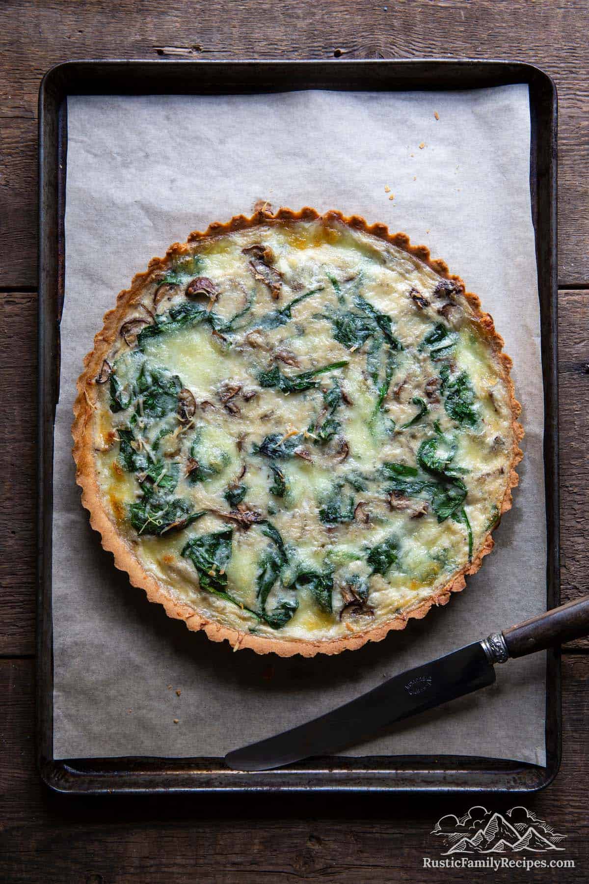 A spinach mushroom quiche on a baking tray lined with parchment paper
