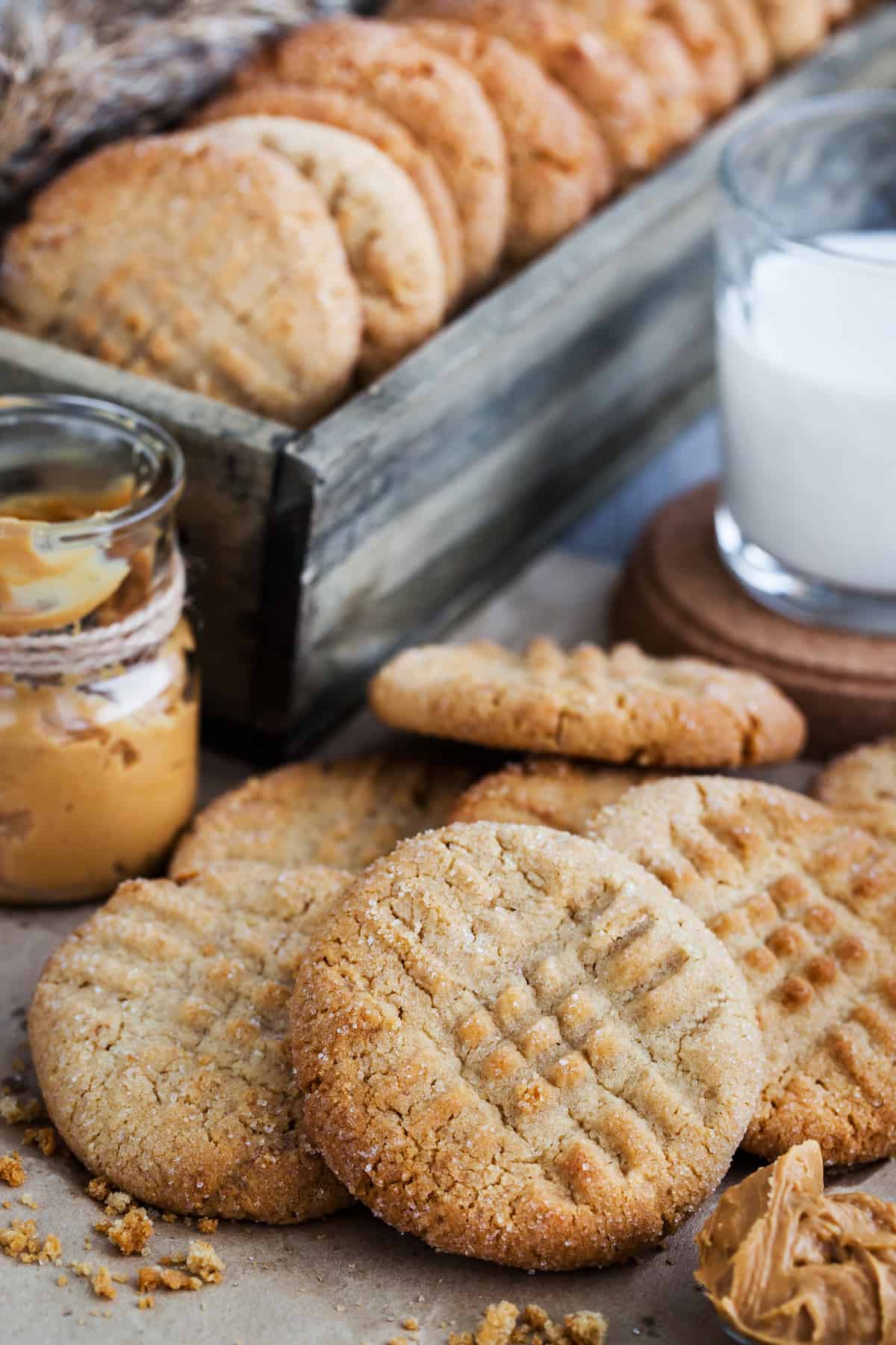 A pile of peanut butter cookies next to a glass of milk