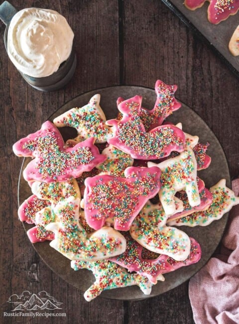 A plate filled with a pile of pink and white frosted animal cookies