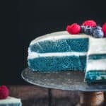A blue matcha cake sliced open with two layers and frosting