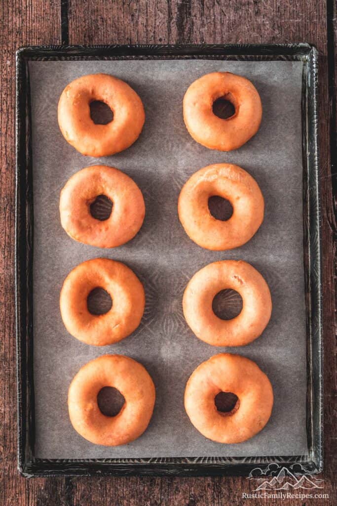 Homemade donuts on a baking sheet ready to be frosted
