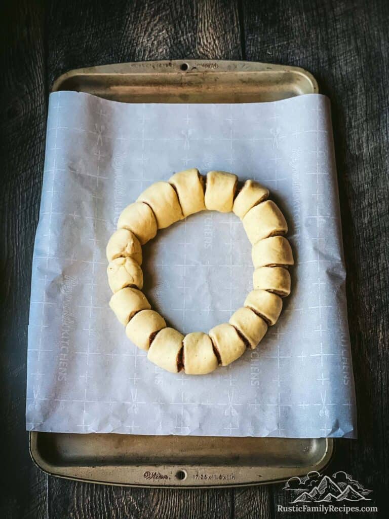 A circle of dough on a baking sheet with cuts in the dough