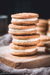 A stack of Biscoff sandwich cookies on a wooden cutting board.