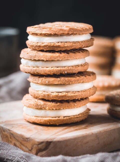 A stack of Biscoff sandwich cookies on a wooden cutting board.