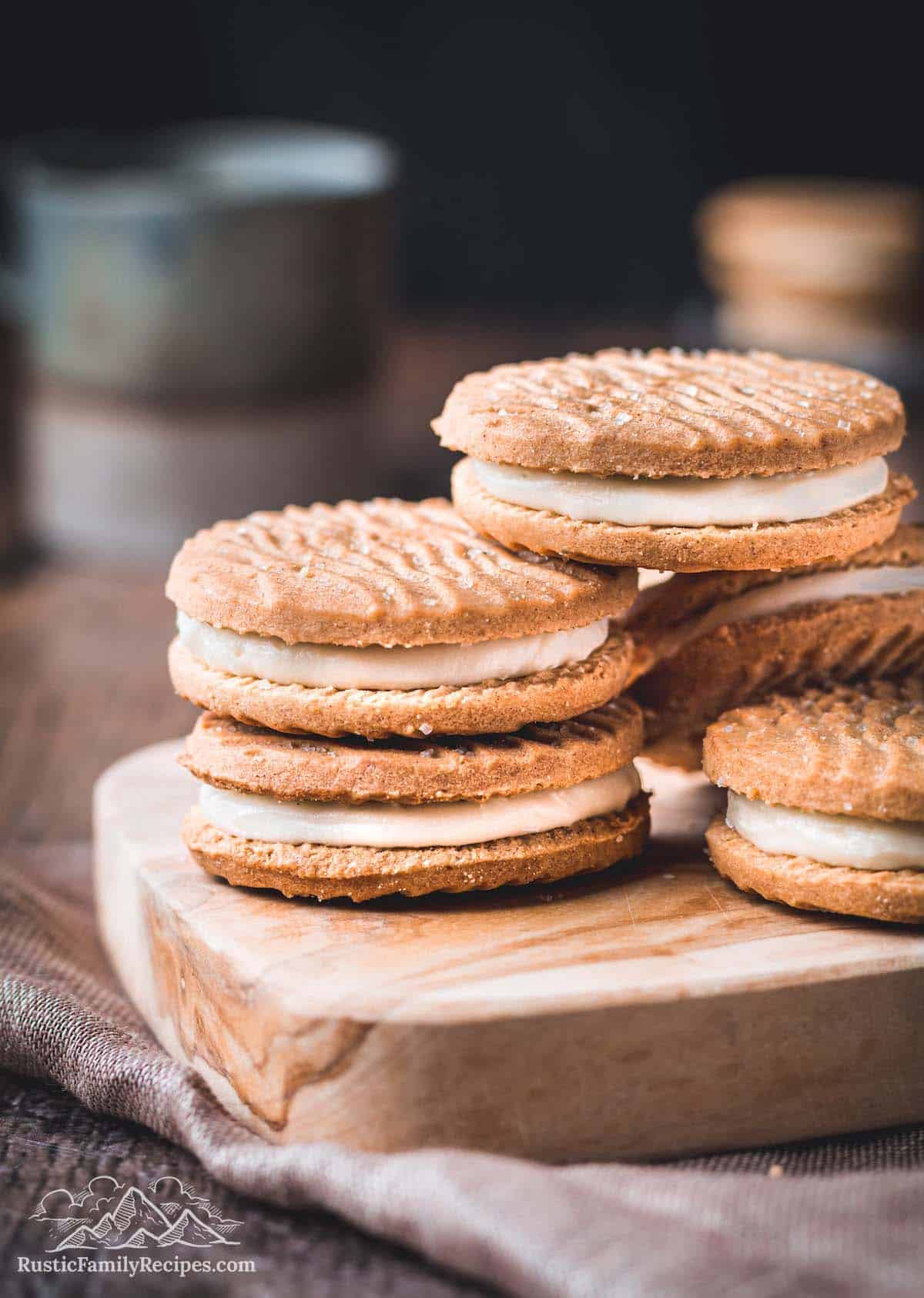 Biscoff sandwich cookies stacked on a wooden board.
