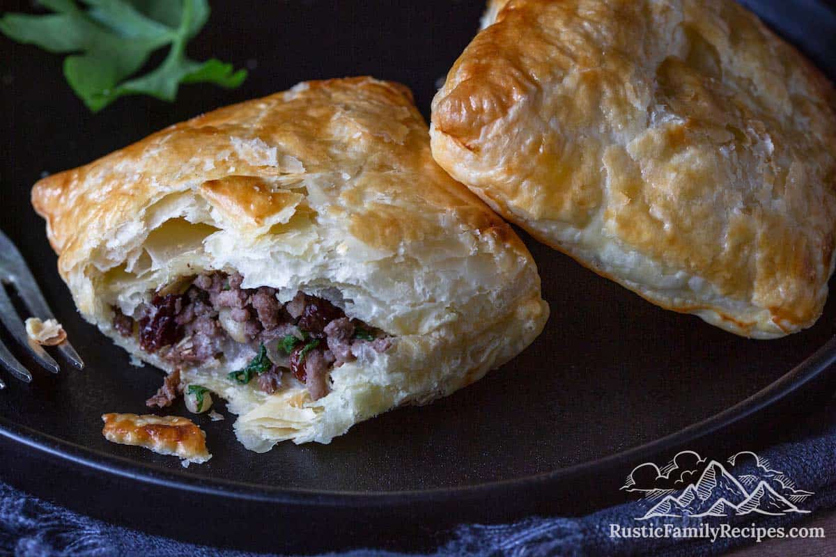 Ground venison meat pies on a black stoneware plate.