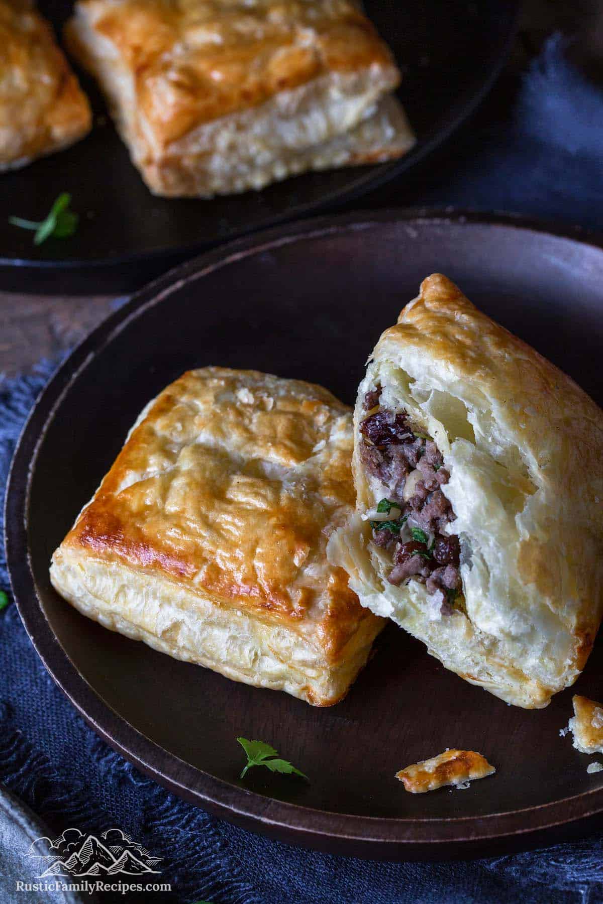 Ground venison meat pies on a black stoneware plate.