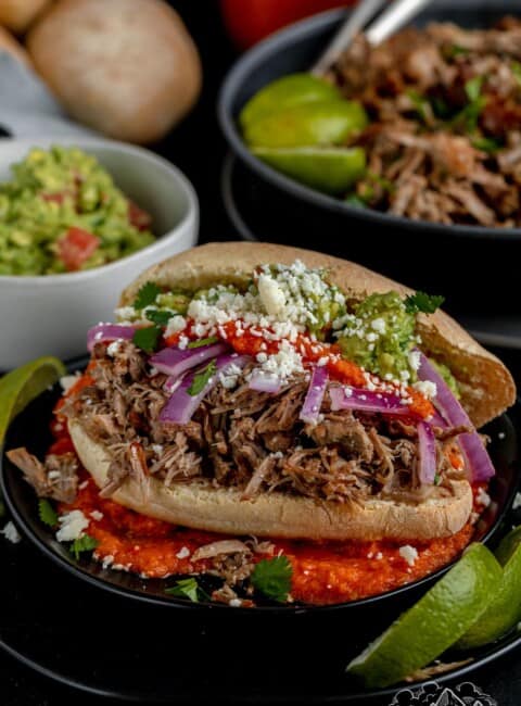 A bolillo stuffed with pork carnitas, guacamole and red onions with cheese