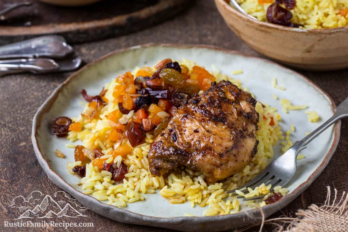 A white plate with saffron rice and paprika chicken