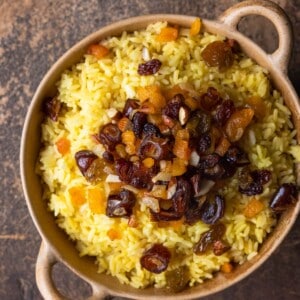 A dutch oven filled with saffron rice topped with dried fruit