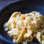 A rustic plate with fluffy scrambled eggs in a pile