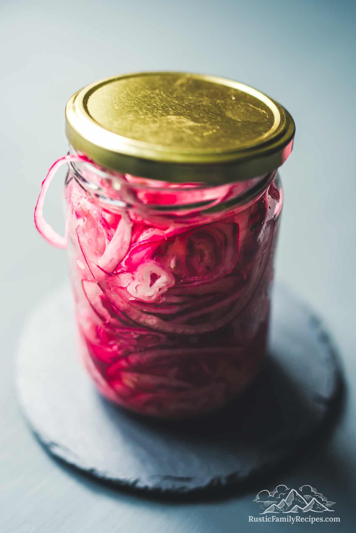 Mason jar with a gold lid filled with pickled red onions
