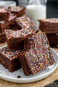 A close-up shot of three homemade brownies on a plate with a raised rim