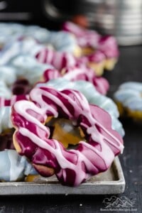 Pink and blue mochi donuts on a baking sheet