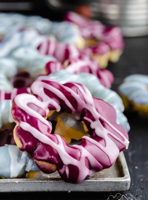 Pink and blue mochi donuts on a baking sheet