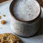 A mug with moon milk and a cookie on a plate