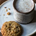 A mug with moon milk and a cookie on a plate