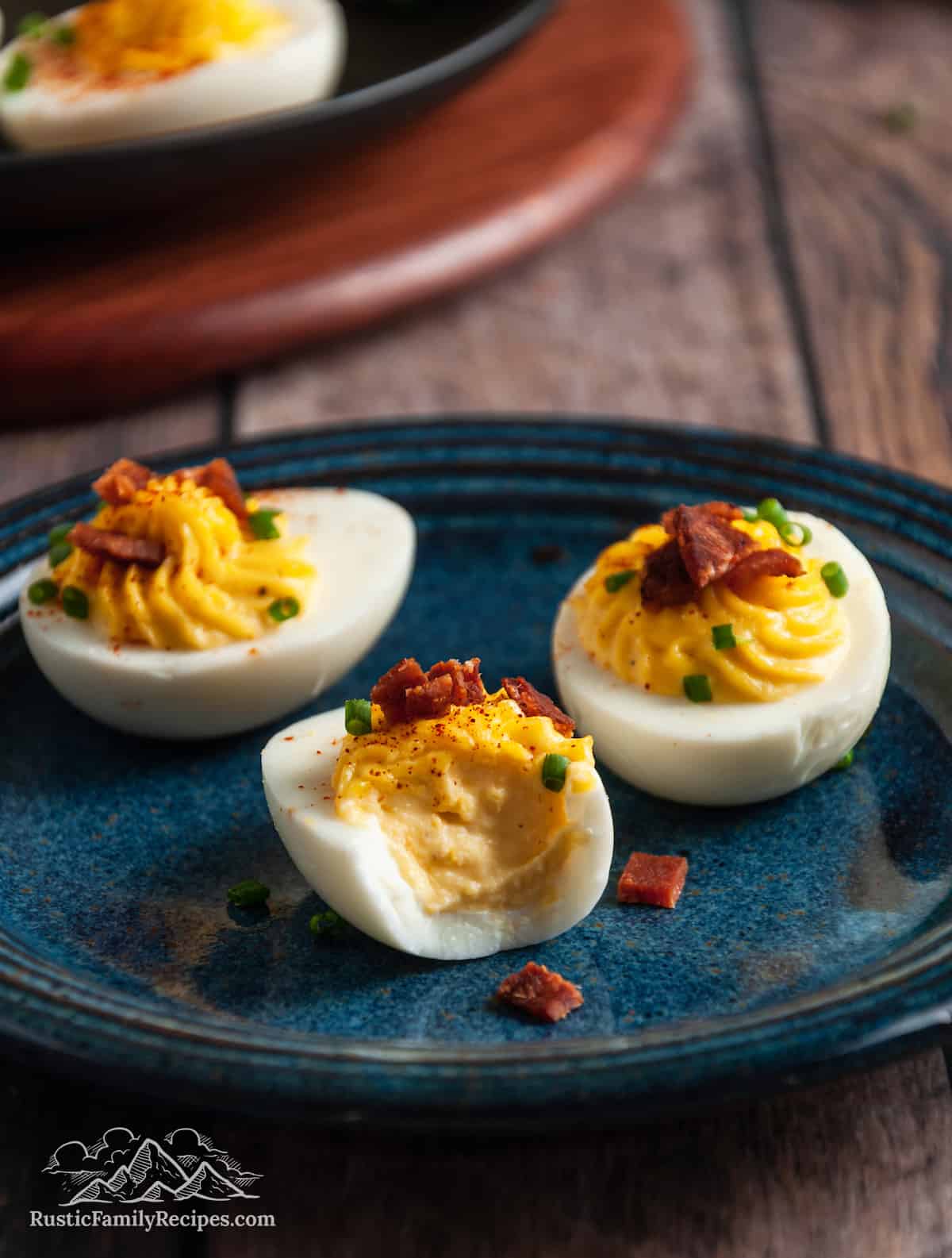 3 deviled eggs on a plate, one with a bite taken out