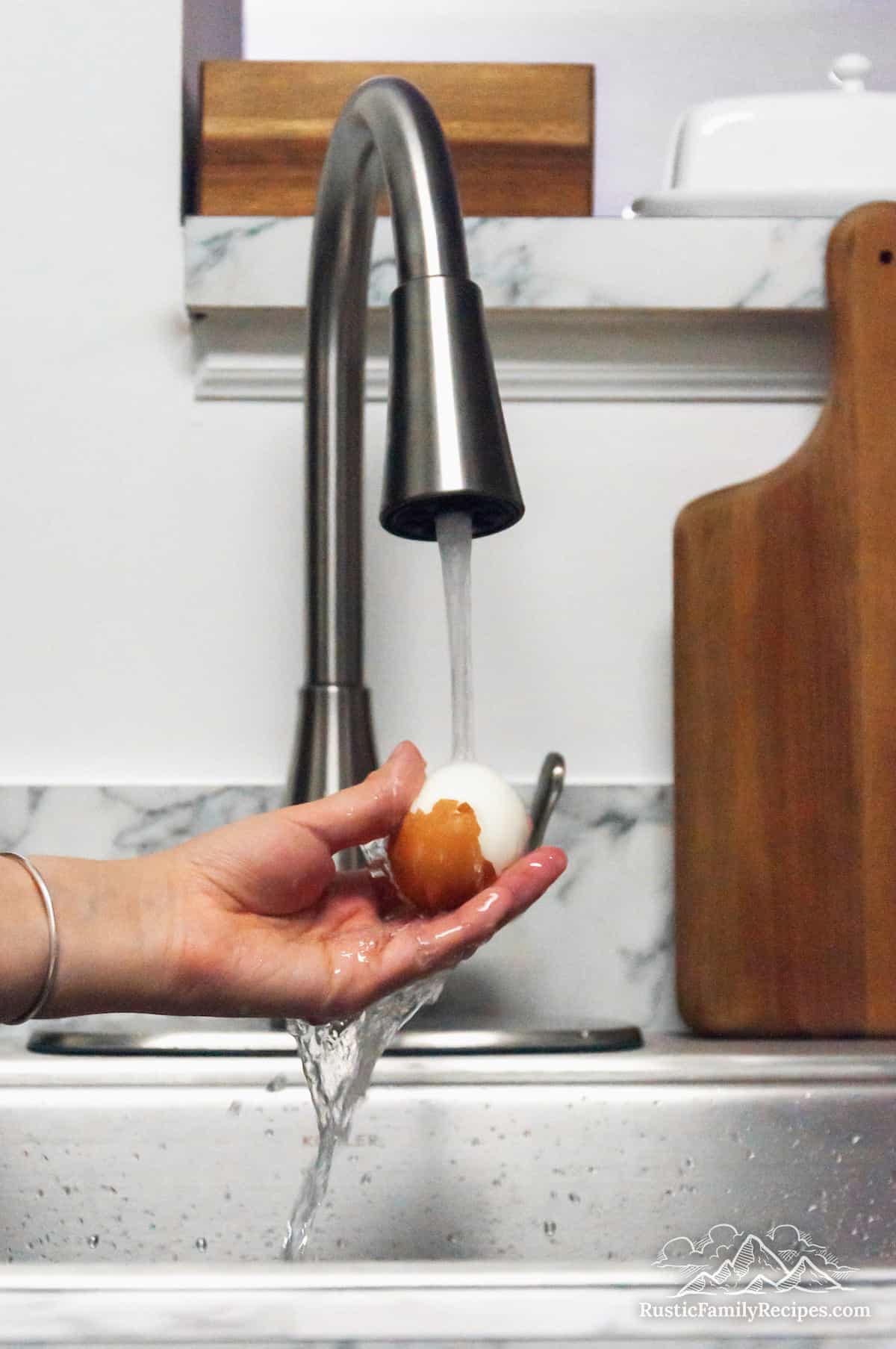 Running an egg under water to peel it